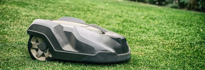 Ein Rasenmähroboter auf grünem Rasen.