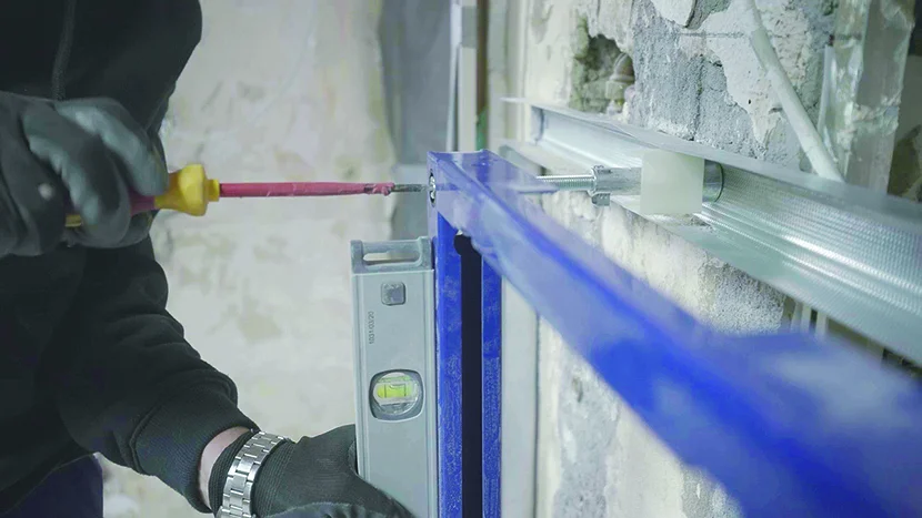 Person montiert Metallrahmen mit Wasserwaage