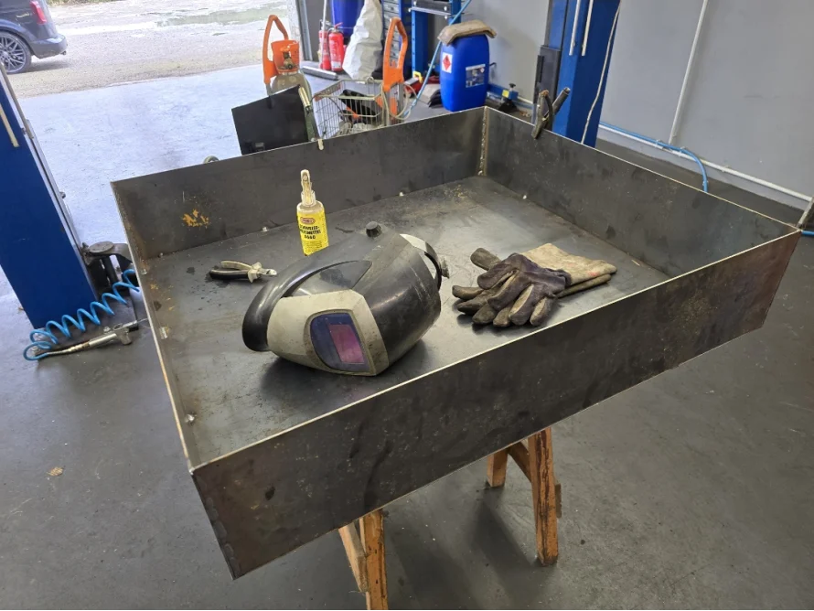 Geschweißtes Metalltablett mit Schweißgerät und Handschuhen