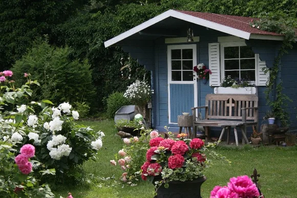 Blaues Gartenhaus mit weißer Tür und Fensterläden