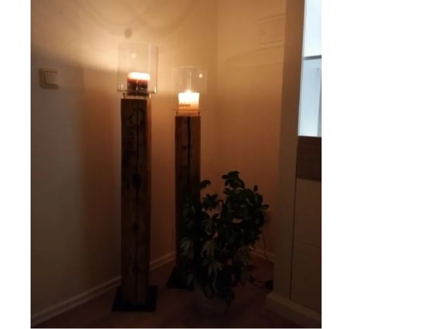 Zwei Kerzenständer aus Holz mit brennenden Kerzen