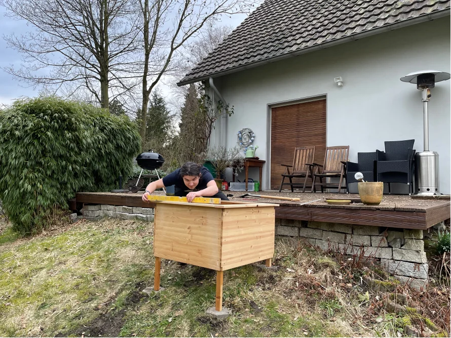 Person baut mit Wasserwaage Holzrahmen auf