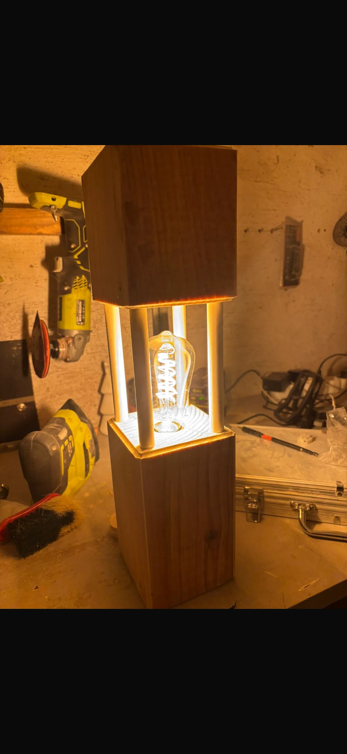 Eine leuchtende, selbstgebaute Tischlampe aus Holz auf einer Werkbank.