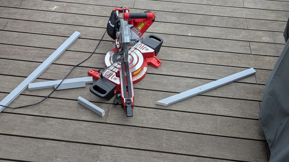 Eine Kappsäge auf Holzdielen mit zugeschnittenen Leisten.