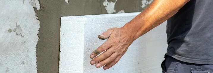 Person befestigt Dämmung an Wand