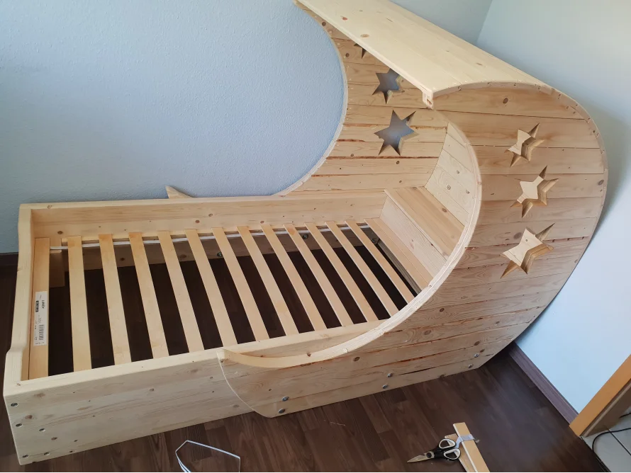 Holzbett in Form eines Halbmondes mit Sternenmuster