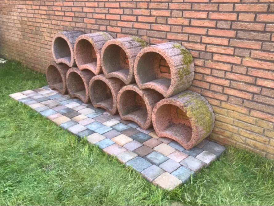 Halbrunde Betonformen an einer Backsteinmauer