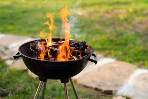 Ein Holzkohlegrill brennt im Garten.
