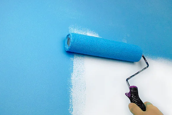 Hand streicht Wand blau