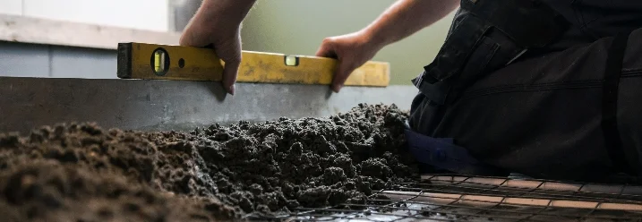 Person überprüft den Untergrund mit einer Wasserwaage
