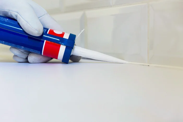 Hand mit Kartuschenpistole verteilt Silikon