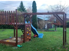 Hölzerner Spielplatz mit Rutsche und Schaukel