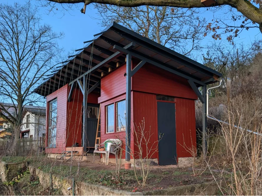 Ein rotes Gartenhaus aus Holz, das sich im Bau befindet.