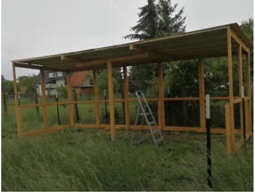 Unfertiger Holzstall mit einer Leiter darin.