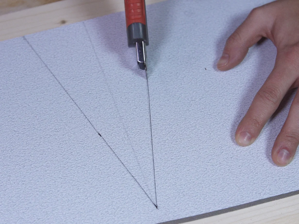 Hand schneidet mit Cuttermesser in eine Unterlage