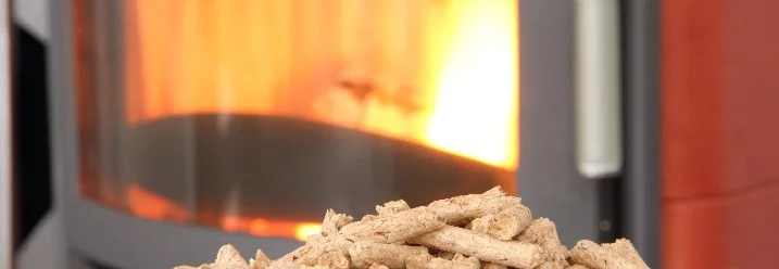 Holzpellets vor einem brennenden Kaminofen