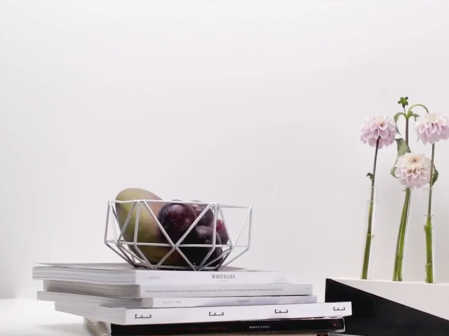 Obstkorb und Blumen auf Bücherstapel