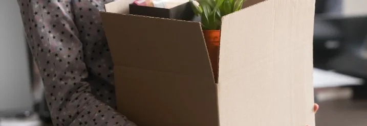 Person mit Karton voller persönlicher Gegenstände