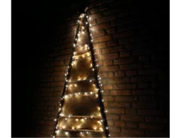 Rustikaler Holz-Weihnachtsbaum mit Lichterkette an Backsteinwand