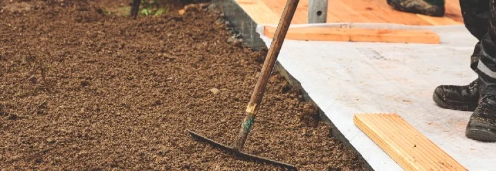 Person harkt Erde im Garten