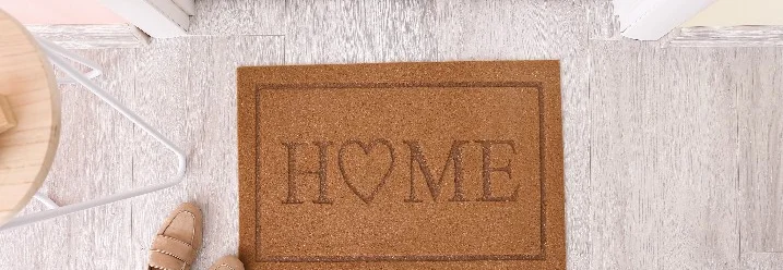 Fußmatte mit der Aufschrift "HOME" vor einer Tür.