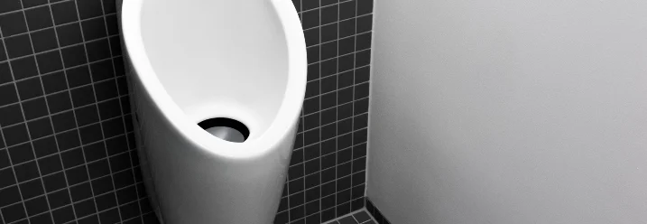 Weißes Urinal an schwarzer Kachelwand