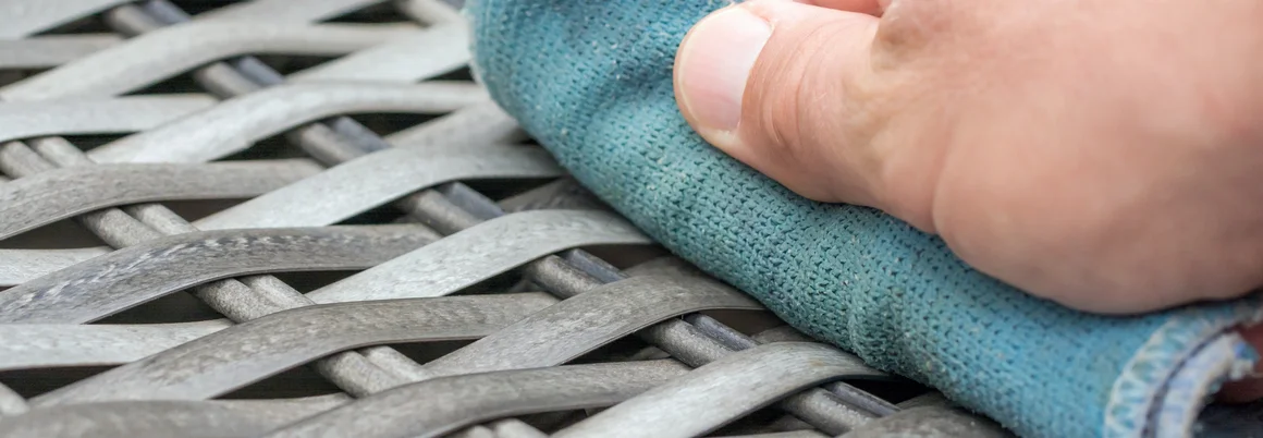 Hand reinigt Gartenmöbel mit Tuch