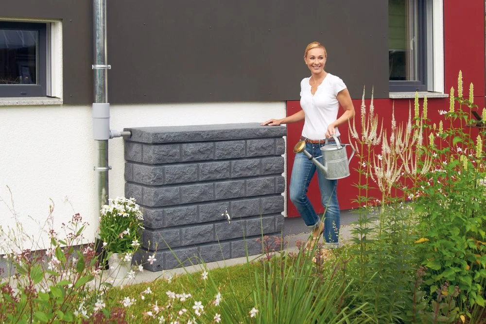 Person mit Gießkanne und Regenwasserspeicher