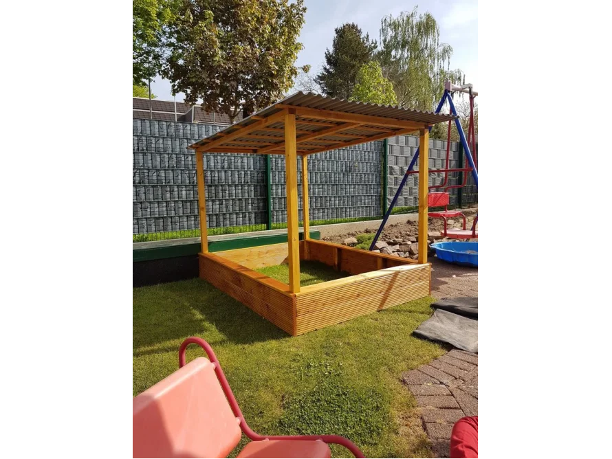 Ein überdachter Sandkasten aus Holz.