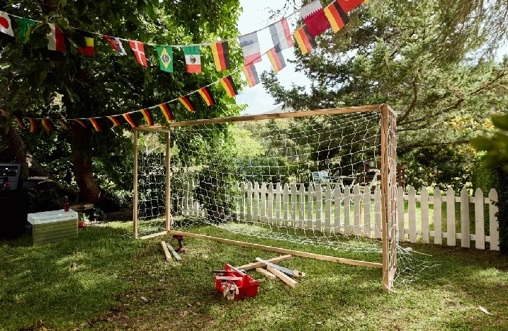 Selbstgebautes Fußballtor mit Werkzeug und Länderflaggen im Garten.