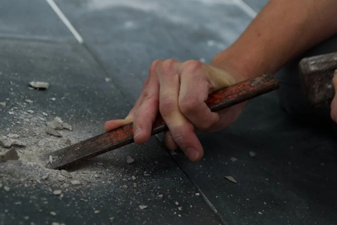 Hand meisselt Fliese auf