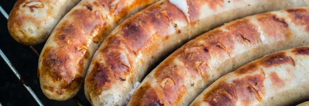 Mehrere goldbraun gegrillte Bratwürste liegen auf dem Grillrost.