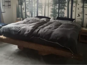 Bett mit Holzrahmen und Wandbild mit Waldmotiv