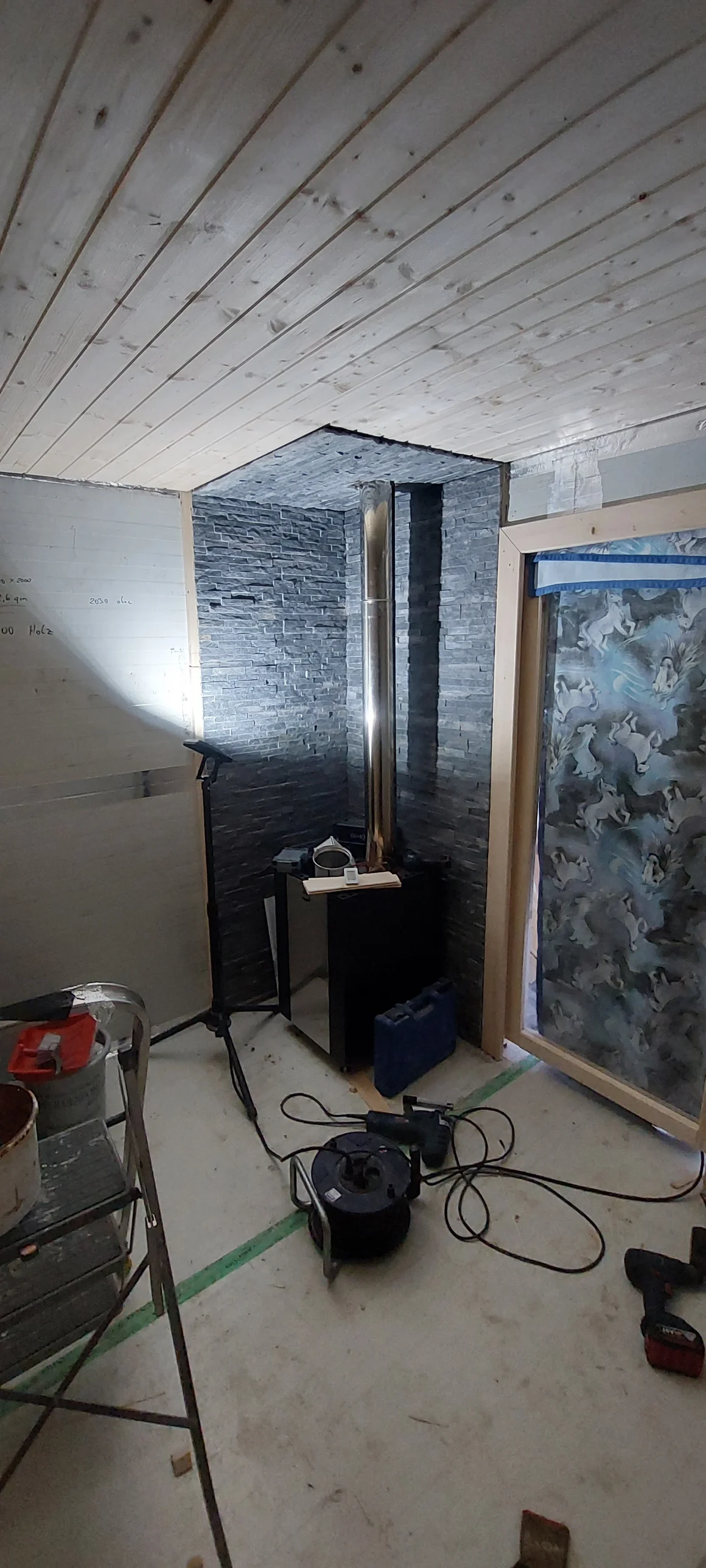 Einbau eines Saunaofens vor einer Steinwand in einem holzverkleideten Raum.