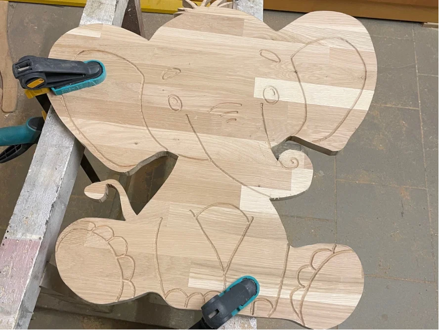 Holzplatte mit Elefanten-Gravur und Schraubzwingen