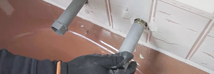 Person hält Rohr über Badewanne