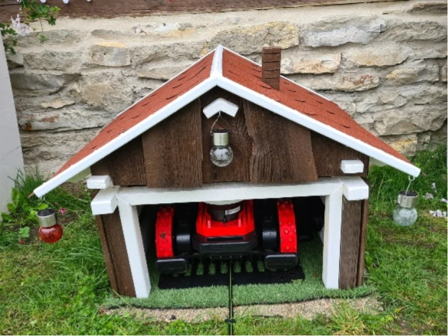 Eine Mähroboter-Garage im Design eines Gartenhauses