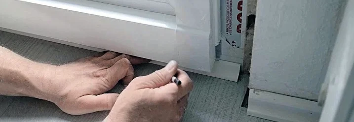 Person markiert Stelle an Türrahmen mit Stift