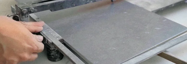 Hand führt Fliese auf Fliesenschneider