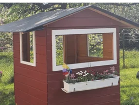 Rotes Gartenhaus mit Blumenkasten