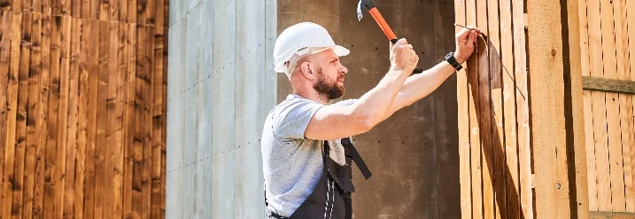 Person baut mit Hammer Holzkonstruktion