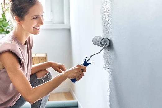 Person streicht Wand mit Farbrolle