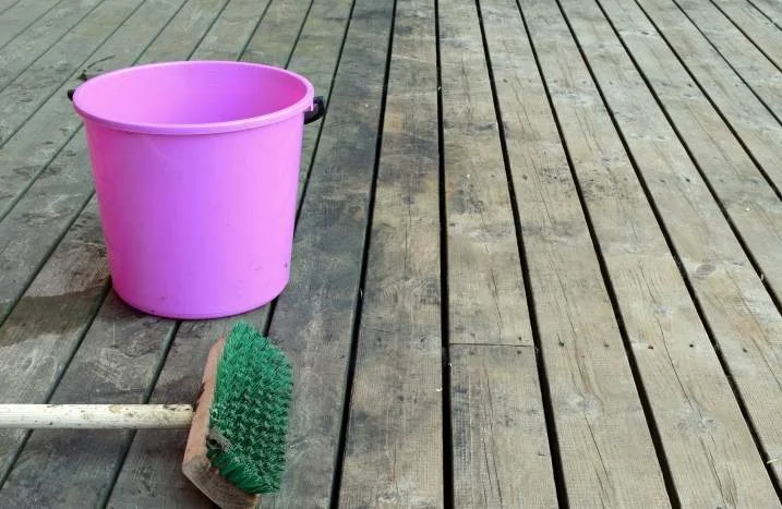 Rosa Putzeimer und Handfeger auf Holzterrasse