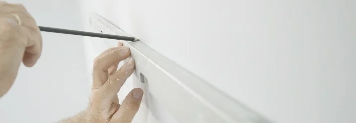 Person zeichnet Linie an Wand