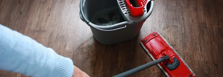 Person wischt Holzboden