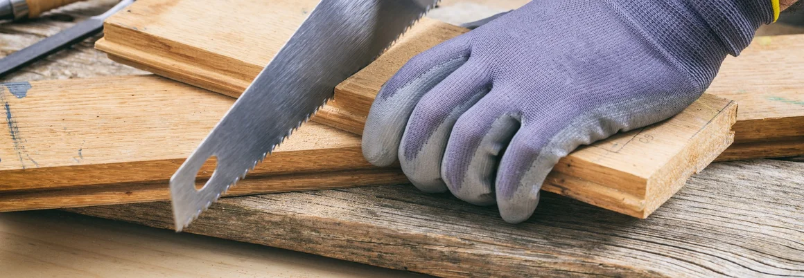 Eine Person sägt mit einer Handsäge ein Stück Holz.