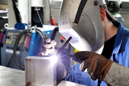 Person mit Schutzmaske schweißt Metall