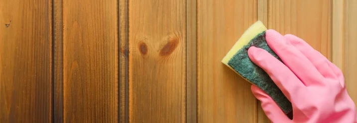 Hand mit Schwamm reinigt Holz