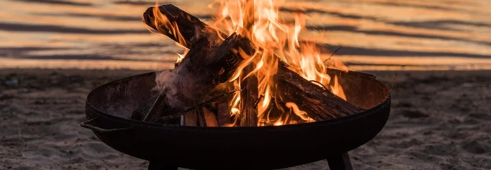Feuerstelle am Strand bei Sonnenuntergang