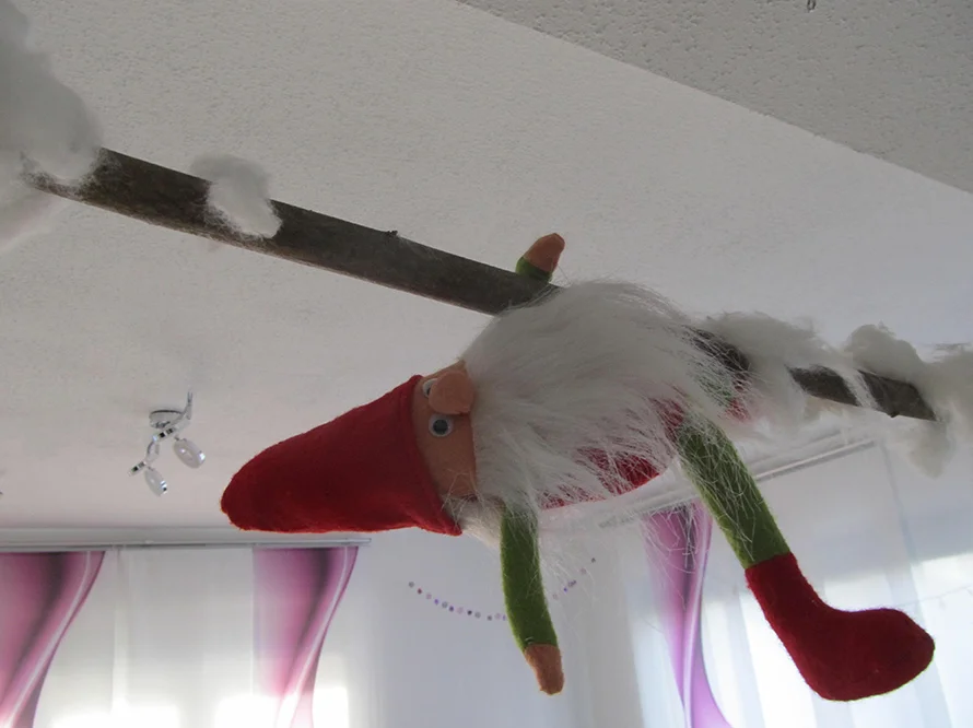 Weihnachtswichtel hängt kopfüber an einer Stange